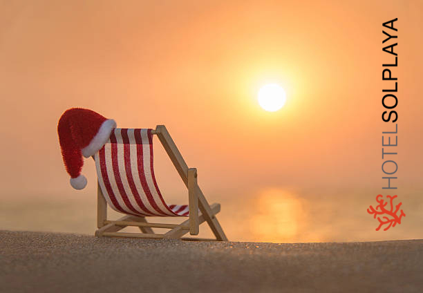 Deckchair with christmas santa hat at ocean beach during sunset
